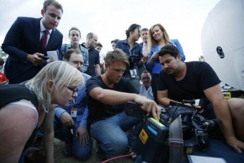 Journalists look at the monitor of a television camera crew who shot footage onboard a P-3 Orion aircraft of objects in the southern Indian Ocean, on March 24, 2014.