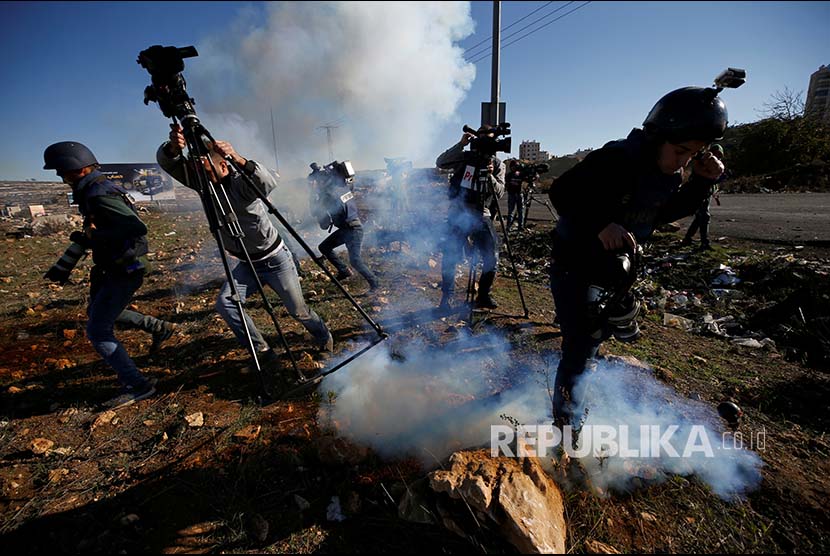 Jurnalis berlarian menghindari gas air mata yang ditembakkan tentara Israel di Kota Ramallah, Tepi Barat, Palestina.