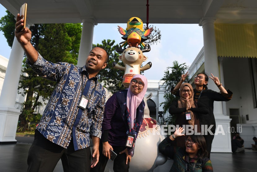 Jurnalis berswafoto dengan maskot Asian Games XVIII di Kompleks Istana Kepresidenan, Jakarta, Senin (14/5).
