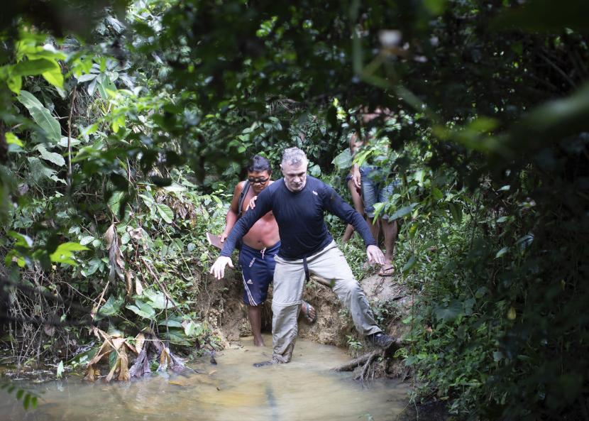 Jurnalis Inggris Dom Phillips (kanan) dan warga suku Yanomami berjalan di Desa Maloca Papiu, negara bagian Roraima, Brasil, November 2019. Kelompok masyarakat adat melaporkan bahwa Phillips dan pakar masyarakat adat Bruno Araujo Pereira hilang di daerah terasing hutan Amazon pada Senin (6/6/2022).