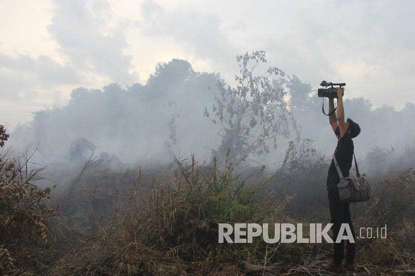 Jurnalis mengambil gambar suasana kebakaran lahan gambut di Desa Peunaga Cut Ujong, Kecamatan Meureubo, Aceh Barat, Aceh, Kamis (4/6/2020). Kebakaran lahan gambut yang diduga akibat puntung rokok tersebut telah menghaguskan tiga hektare lahan milik warga setempat. 