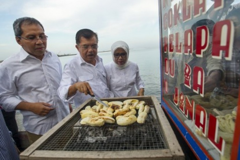 Jusuf Kalla (tengah), bersama istri Ny Mufidah Kalla (kanan), dan Walikota Makassar, Danny Pomanto (kiri), membeli panganan khas tradisional Pisang Epe saat mengunjungi Pantai Losari, Makassar, Sulsel, Kamis (12/6).