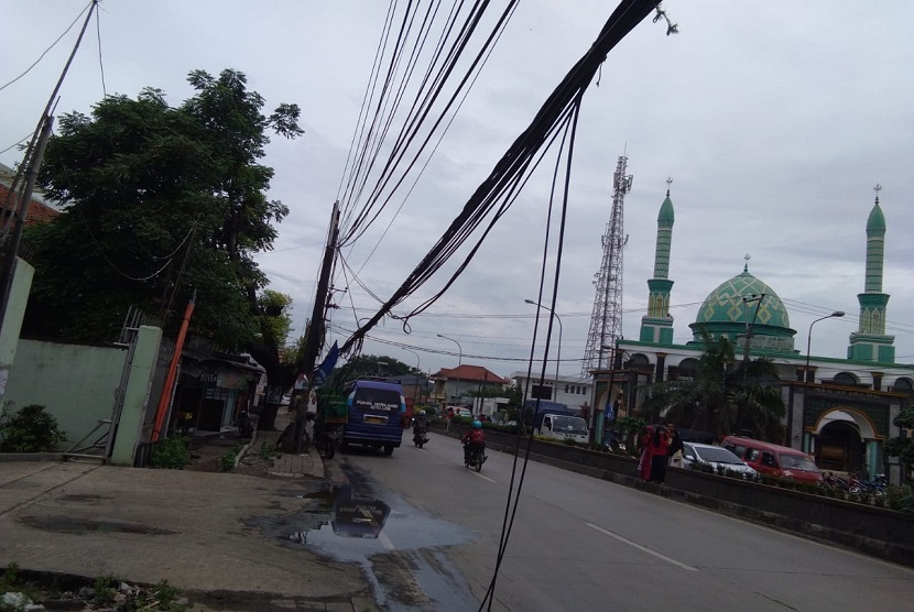 Kabel listrik di Jalan Raya Imam Bonjol, Kabupaten Bekasi, terlepas dan terjuntai hingga ke trotoar jalan