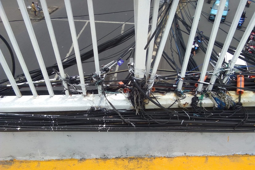 Kabel listrik di Jembatan Penyeberangan Orang (JPO) Jalan Dewi Sartika,  Jakarta Timur,  kondisinya sangat semrawut. Kabel-kabel ini menjuntai dan terikat di sisi JPO. 