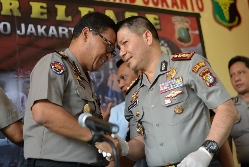 Kabid Humas Polda Metro Jaya Kombes Pol Argo Yuwono (kiri) berjabat tangan dengan Kapolres Metro Jakarta Barat Kombes Pol Roycke Harry Langie seusai memberikan keterangan terkait tahanan Polres Metro Jakarta Barat yang kabur di RS Polri Kramat Jati, Jakarta, Minggu (17/9). 