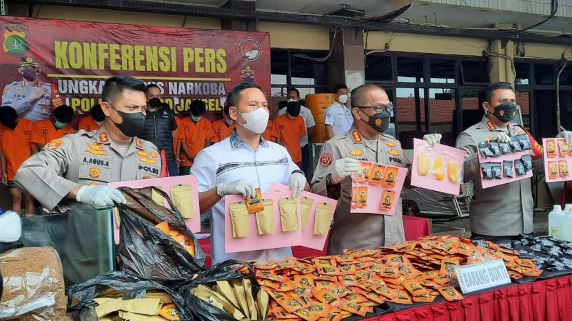 Kabid Humas Polda Metro Jaya Kombes Pol Yusri Yunus (kedua dari kanan) memperlihatkan barang bukti tembakau sintesis yang dikemas dalam bungkusan makanan ringan, di Mapolres Jakarta Selatan, Senin (31/5). 