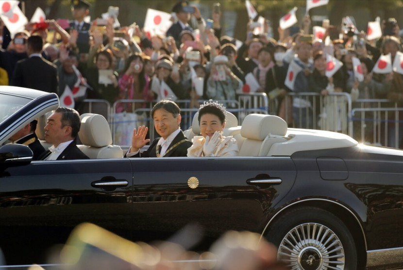 Kaisar Jepang Naruhito dan Permaisuri Masako melambaikan tangan kepada warga saat parade kekaisaran di Tokyo, Ahad (10/11).