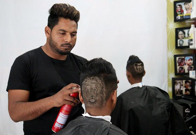 Kakak-adik Rajwinder Singh Sidhu dan Gurwinder Singh Sidhu di kota Dabwali memberikan potongan rambut berbentuk gambar pilihan pelanggan.