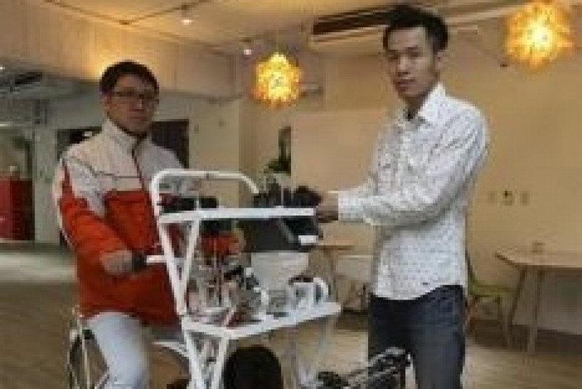 Kamm Kai-yu (right), a co-founder of boutique design studio Fabraft, displays a bicycle with a 3D printer installed in front, in Taipei March 13, 2014.