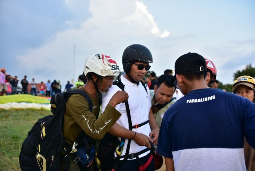 Kandidat Gubernur Jabar Ridwan Kamil bersiap terbang dengan paralayang di Majalengka, Ahad (18/3).