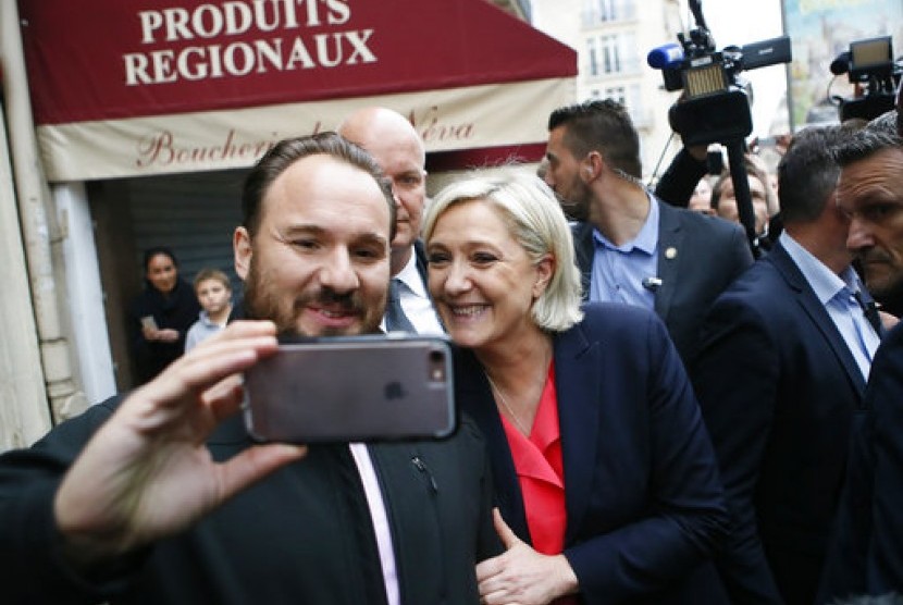 Kandidat presiden Prancis dari kubu sayap ekstrem kanan Marine Le Pen berswafoto saat meninggalkan markas Partai Front National di Paris, Ahad, 7 Mei 2017.