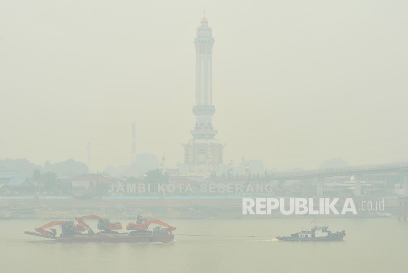 Kapal tongkang membawa alat berat melintasi Sungai Batanghari yang diselimuti kabut asap dari karhutla di Jambi, Sabtu (21/9/2019).