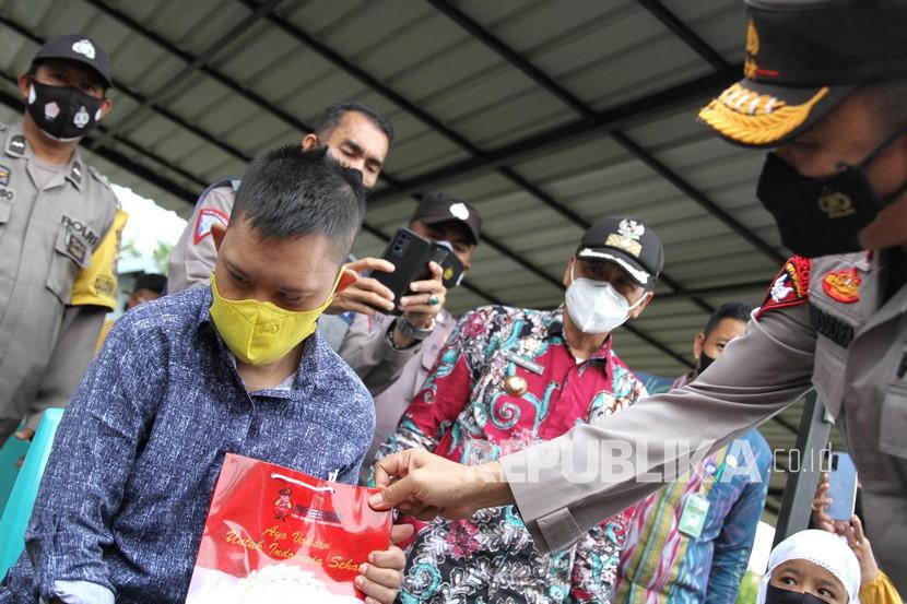 Kapolda Sulawesi Tenggara Irjen Pol Yan Sultra Indrajaya (kanan) memberikan bingkisan ke seorang tuna netra saat kegiatan vaksinasi di Polsekta Mandonga, Kendari, Sulawesi Tenggara, Kamis (5/8/2021). Wali Kota Kendari meminta camat-lurah berperan pada vaksinasi anak.