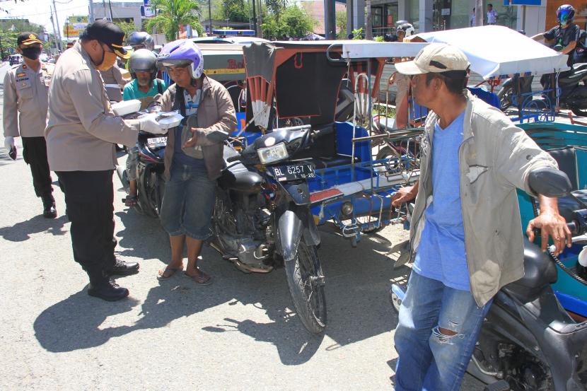 Petugas kepolisian memberikan bantuan paket nasi kotak dan masker kepada pengendara becak motor dan juru parkir (ilustrasi)