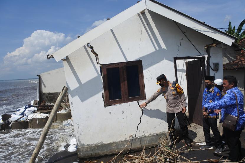 Kapolres Situbondo AKBP Andi Sinjaya (kiri) meninjau rumah warga yang rusak terkena banjir rob atau air laut pasang di Desa Landangan, Kapongan, Situbondo, Jawa Timur, Jumat (17/6/2022). Sebanyak 90 rumah di desa tersebut terdampak banjir rob serta angin kencang dan tujuh rumah di antaranya rusak. 
