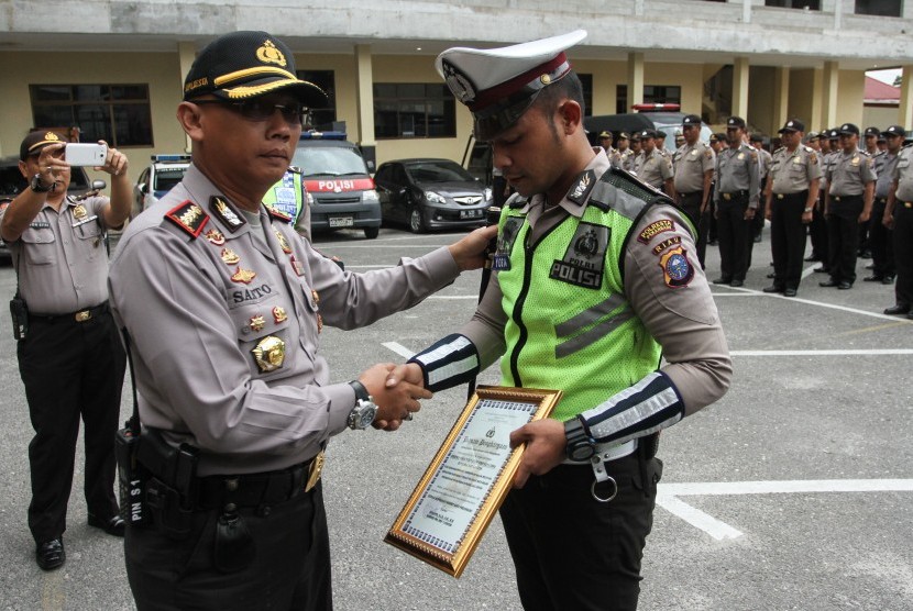 Kapolresta Pekanbaru Kombes Pol Susanto (kiri) memberikan penghargaan kepada Bripda Yoga Vernando anggota Polantas Polresta Pekanbaru yang menjadi korban pemukulan oknum TNI AD di halaman Mapolresta Pekanbaru, Riau, Jumat (11/8). 