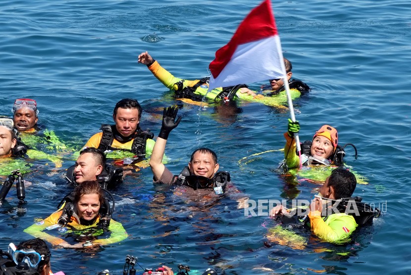 Kapolri Jendral Pol. Tito Karnavian (tengah) bersama istri Ny. Tri Tito Karnavian (mengibarkan bendera) saat naik ke permukaan usai penyelaman massal di kawasan pantai Megamas, Manado, Sulawesi Utara, Sabtu (3/8/2019). 