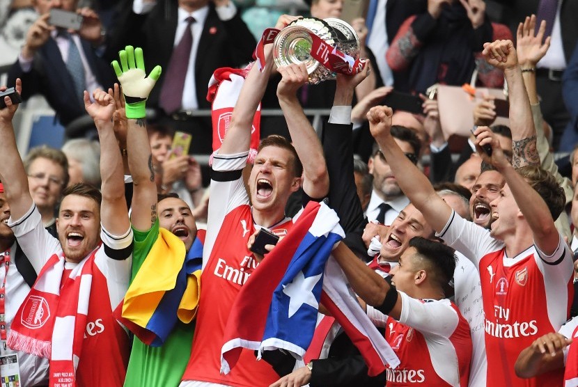 Kapten Arsenal, Per Mertesacker mengangkat trofi Piala FA setelah timnya berhasil mengalahkan Chelsea pada laga final di Stadion Wembley, Ahad (28/5) dini hari WIB.