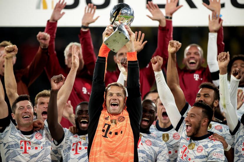 Kapten Bayern Muenchen Manuel Neuer mengangkat trofi Piala Super Jerman 2021.