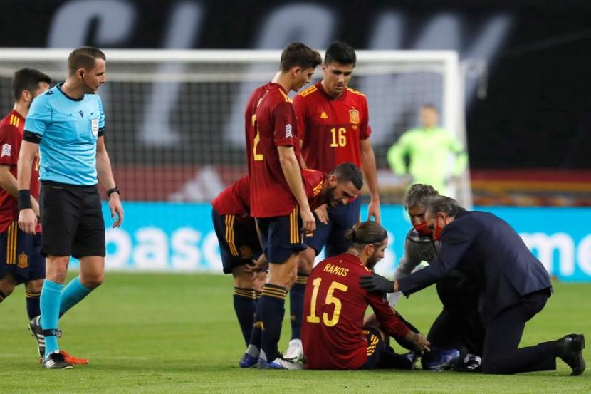 Kapten Spanyol Sergio Ramos (duduk) mendapatkan perawatan saat cedera ketika melawan Jerman pada laga UEFA Nations League, Rabu (18/11) dini hari WIB.