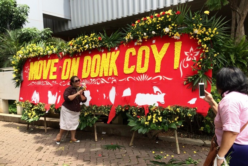 Warga berfoto dengan latar belakang karangan bunga bertuliskan Move On Donk Coy! di halaman Kantor Balai Kota DKI Jakarta