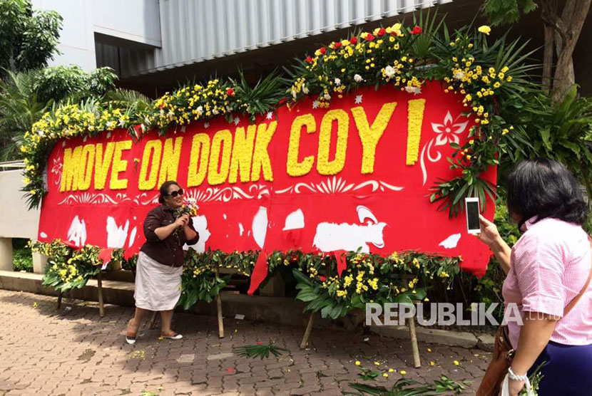 Warga berfoto dengan latar belakang karangan bunga bertuliskan Move On Donk Coy ! di halaman Kantor Balai Kota DKI Jakarta