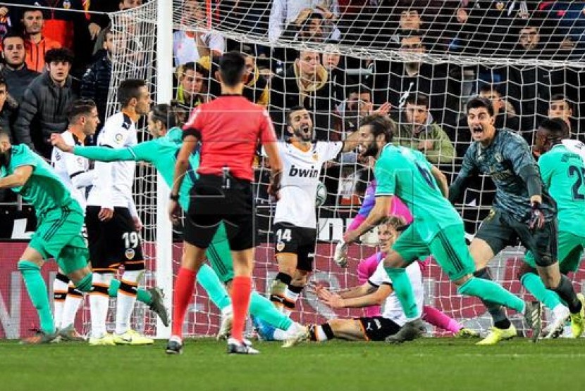Karim Benzema saat mencetak gol ke gawang Valencia, Ahad Malam.