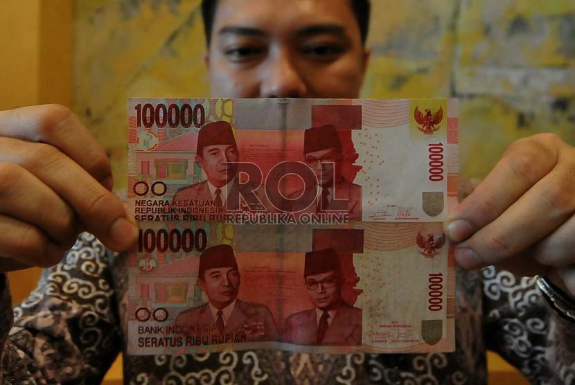 Karyawan Bank Indonesia memerlihatkan uang kertas pecahan Rp. 100.000 baru (atas) dan lama (bawah) usai launching uang tersebut di Bank Indonesia,Jakarta, Senin (18/8). (Republika/Prayogi)