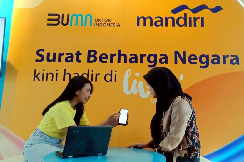 Karyawan Bank Mandiri menjelaskan instrumen investasi Surat Berharga Negara (SBN) Ritel di Livin by Mandiri kepada nasabah di Jakarta, Senin (6/3/2023). 