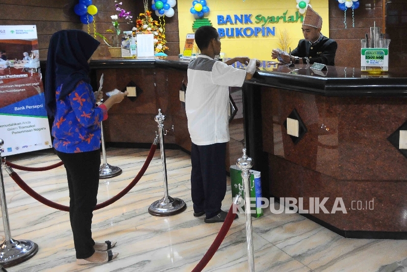  Karyawan melayani nasabah di Bank Syariah Bukopin, Jakarta, Rabu (11/1).