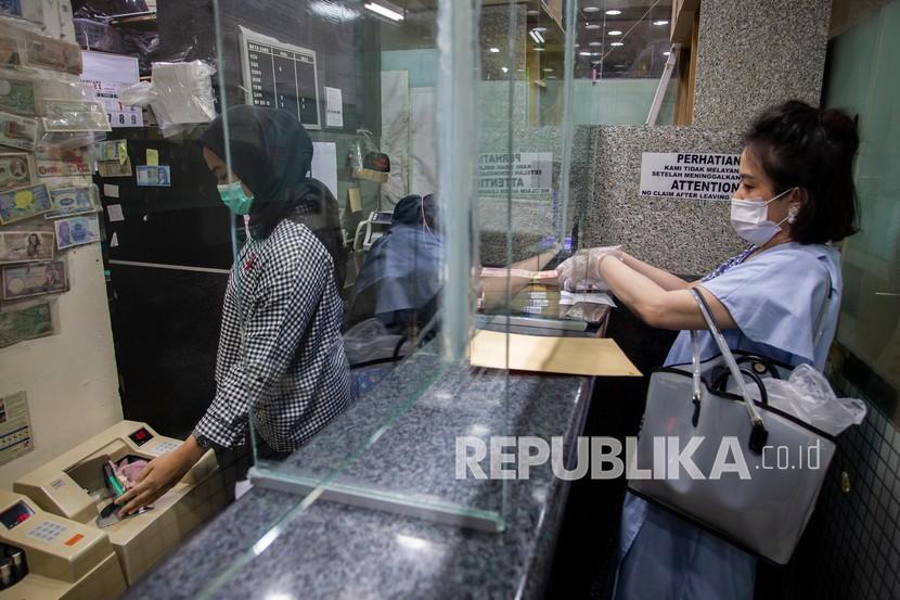 Karyawan melayani nasabah di salah satu gerai penukaran uang asing di Jakarta