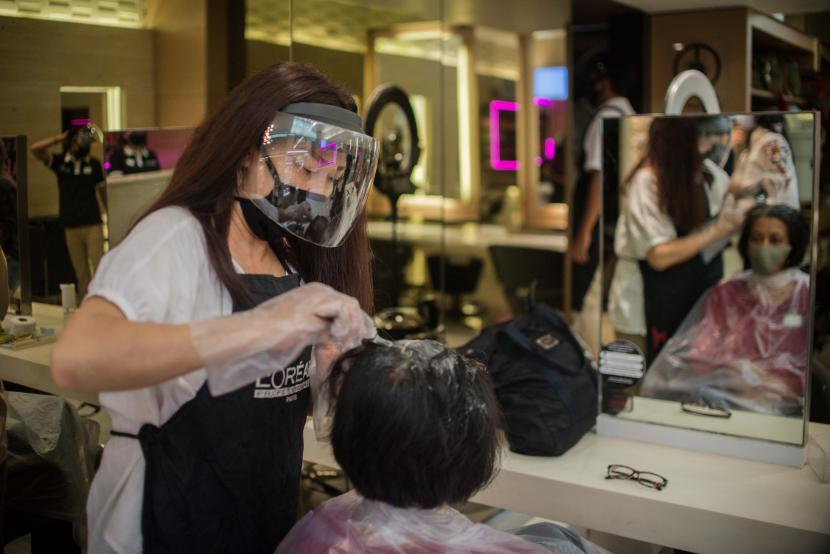 Karyawan melayani pelanggan yang melakukan perawatan rambut di Alfons Salon, Jakarta.