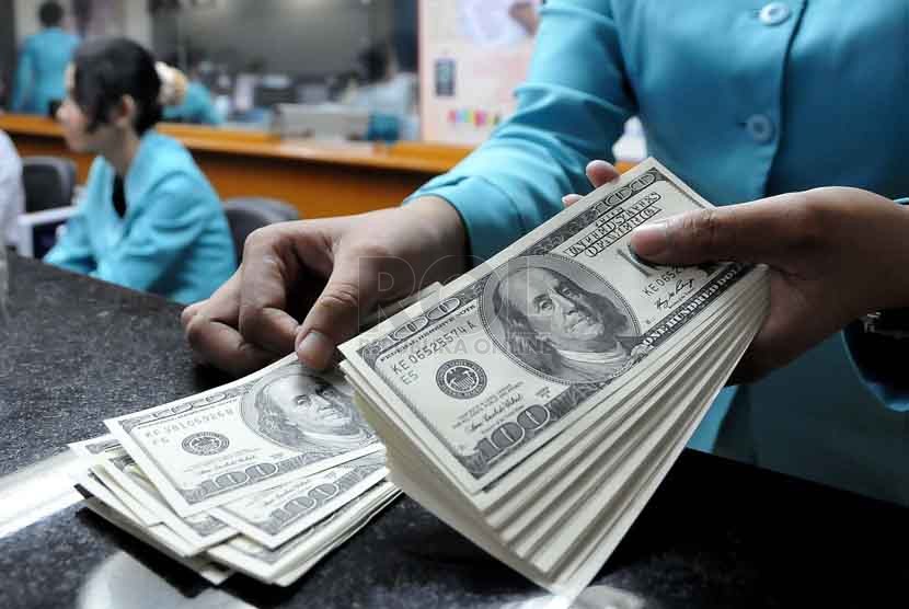 Karyawan melayani penukaran Dollar Amerika di salah satu jasa penukaran valuta asing di Jakarta,Selasa (7/10). (Republika/Prayogi)