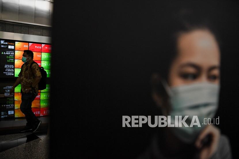 Karyawan melintas di dekat layar yang menampilkan pergerakan saham di Bursa Efek Indonesia, Jakarta, Jumat (8/10/2021). 