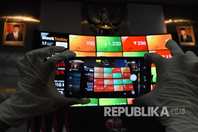 Karyawan mengambil gambar layar pergerakan harga saham di gedung Bursa Efek Indonesia.