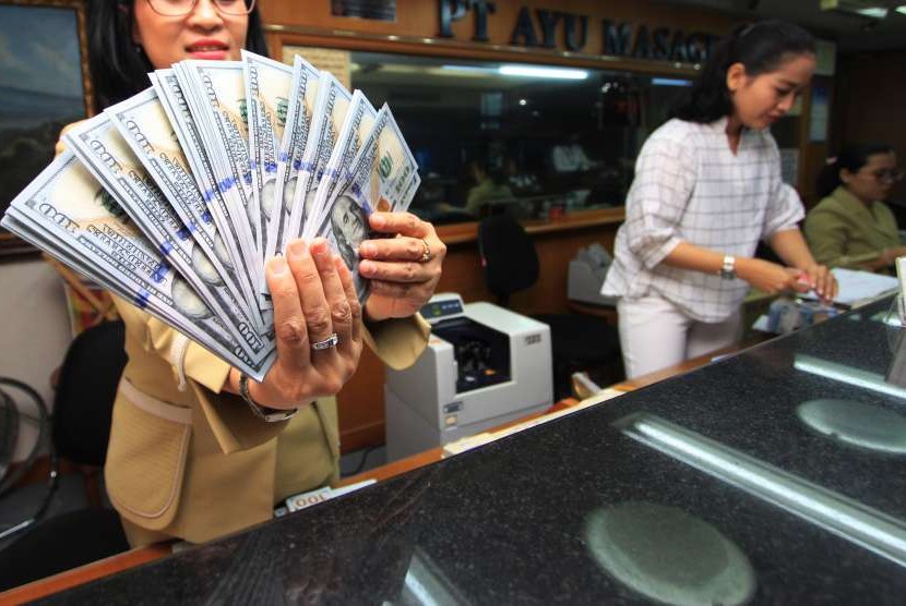 Karyawan menghitung mata uang Dollar AS di gerai jasa penukaran uang asing di Jakarta, Senin (13/8). 