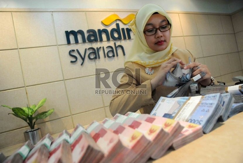  Karyawan menghitung uang di bangking hall Bank Syariah Mandiri, Jakarta, Selasa (17/11).