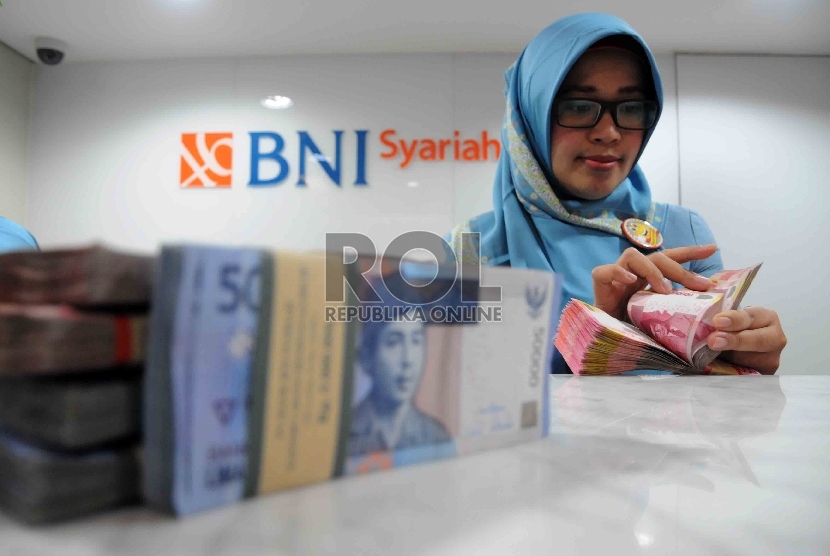  Karyawan menghitung uang di Banking Hall Bank BNI Syariah, Jakarta, Rabu (2/12).