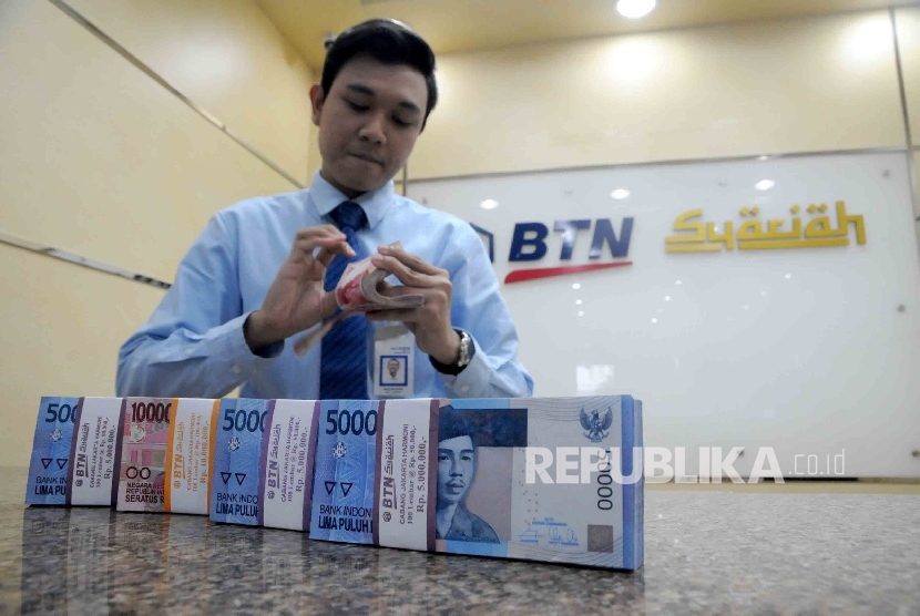 Karyawan menghitung uang di banking hall Bank BTN Syariah, Jakarta, Kamis (21/1).