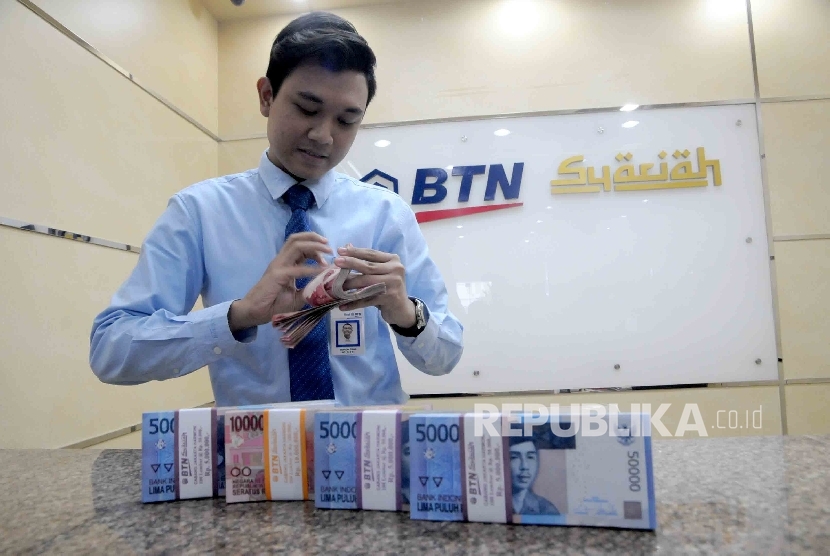 Karyawan menghitung uang di banking hall Bank BTN Syariah, Jakarta, Kamis (21/1). 
