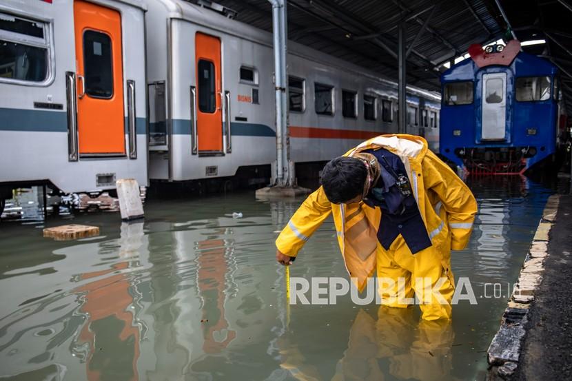 Karyawan mengukur ketinggian banjir pada lintasan kereta api di Stasiun Tawang, Semarang, Jawa Tengah, Sabtu (6/2/2021). Akibat banjir setinggi hingga 70 cm tersebut, PT KAI (Persero) DAOP 4 Semarang mengalihkan sejumlah rute perjalanan kereta api.