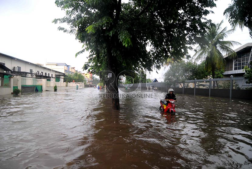   Seorang karyawan mendorong sepeda motornya melewati banjir yang menggenangi Kawasan Industri Pulo Gadung, Jakarta Timur, Rabu (5/2).    (Republika/ Wihdan)