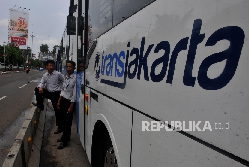  Karyawan Transjakarta berdiri disamping bus yang terparkir di kawasan Kebayoran Baru, Jakarta Selatan, Rabu (27/9). 
