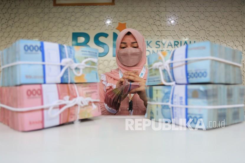 Karyawati Bank Syariah Indonesia (BSI) menghitung uang rupiah di Kantor Cabang Pembantu (KCP) Daud Beureueh, Banda Aceh, Aceh. Otoritas Jasa Keuangan (OJK) mencatat aset perbankan syariah sebesar Rp 686,29 triliun pada April 2022. Adapun realisasi ini tumbuh 12,71 persen secara year on year.