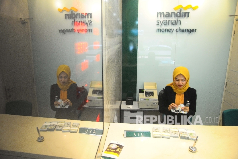  Karyawati menghitung dolar AS di Banking Hall Bank Syariah Mandiri, Jakarta, Selasa (18/4).