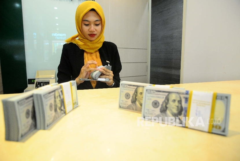  Karyawati menghitung dolar AS di Banking Hall Bank Syariah Mandiri, Jakarta, Selasa (18/4). 
