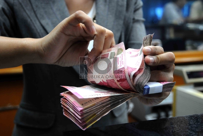  Karyawati menghitung mata uang rupiah di salah satu tempat penukaran valuta asing di Jakarta, Selasa (15/12). 