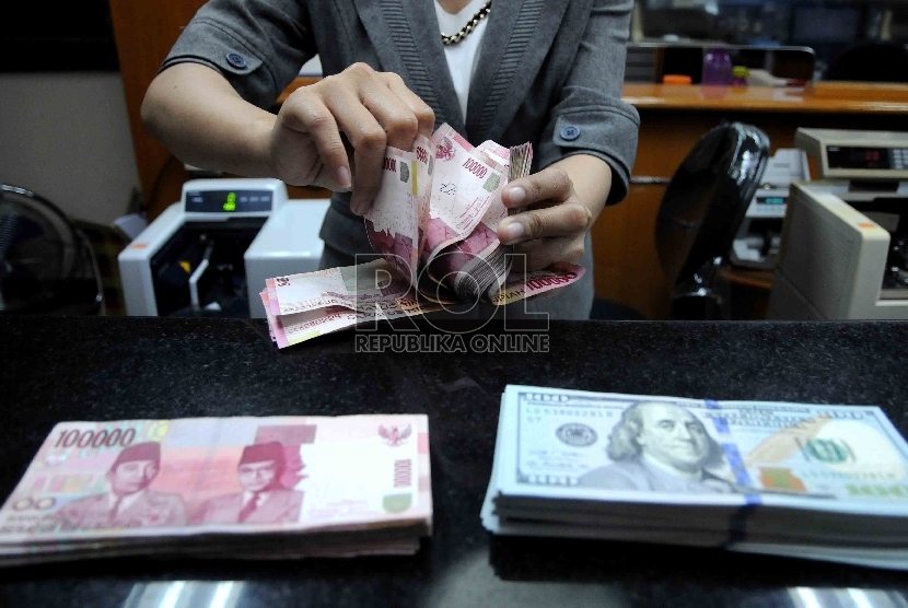 Karyawati menghitung mata uang rupiah di salah satu tempat penukaran valuta asing di Jakarta, Selasa (15/12).