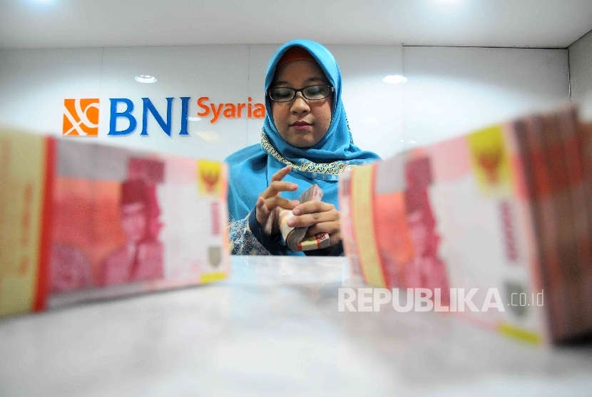 Karyawati menghitung uang di banking Hall bank BNI Syariah, Jakarta, Senin (23/1).