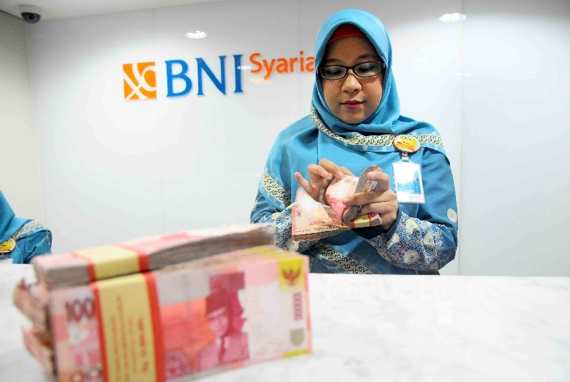 Karyawati menghitung uang di banking Hall bank BNI Syariah, Jakarta. ilustrasi